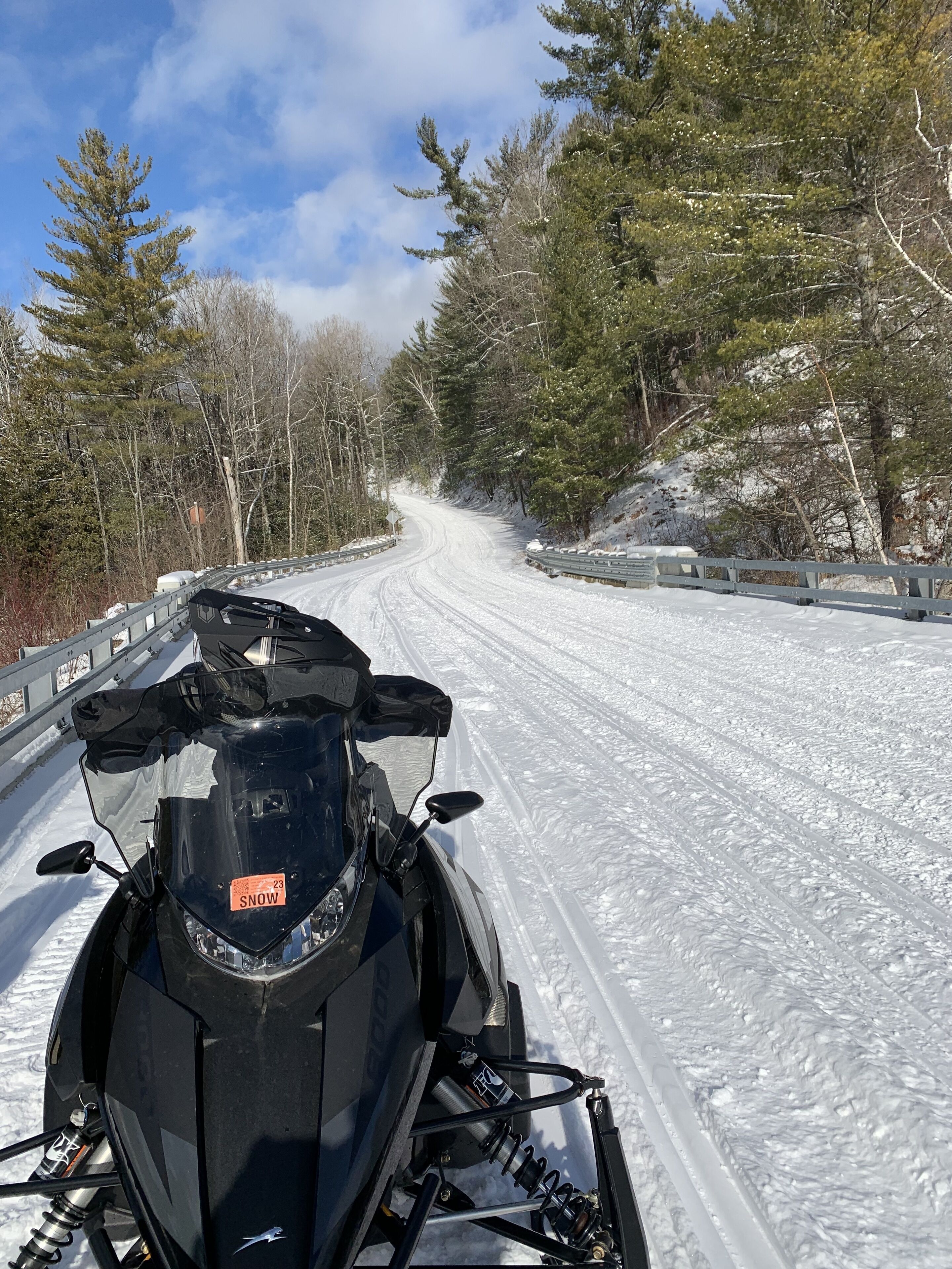 Un vehículo de nieve en un camino cubierto de nieve, flanqueado por árboles.