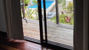 Una habitación con puerta de vidrio corredera que da a un balcón con piscina.