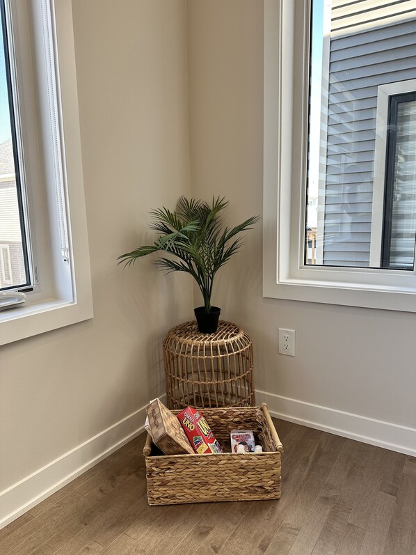 A corner room with a large window, a potted plant, and a wicker basket with items. - The Stay Lounge (Ottawa)