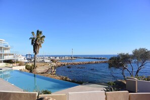 Resort com piscina, vista para o mar e um molhe rochoso.