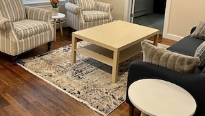 A living room with striped sofas, a coffee table, and a TV mounted on the wall. - Narragansett- 1 block to Narrow River! (Narragansett)