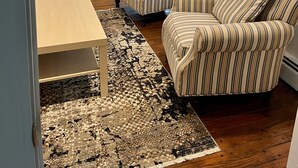 A living room with two striped armchairs, a small table, and a patterned rug. - Narragansett- 1 block to Narrow River! (Narragansett)