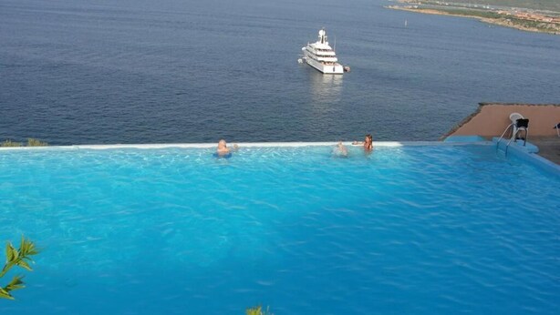 Una piscina infinita con vista al mar y un yate.