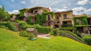Una villa en una ladera con varios balcones, exuberante vegetación y un sendero de piedra que conduce a la entrada.