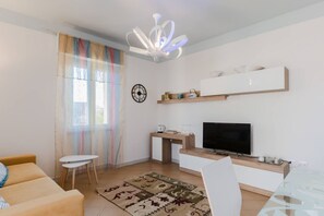 Una sala de estar moderna con un sofá, televisor y una pequeña mesa.