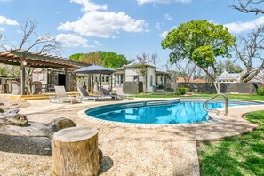 Un jardin avec une piscine, des chaises longues et un patio couvert.