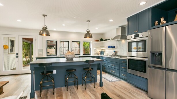 Una cucina moderna con un'isola grande, elettrodomestici in acciaio inossidabile e mobili blu.