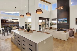 Sleek open kitchen and living area with high ceilings, designer lighting, and mountain views—made for stylish entertaining.