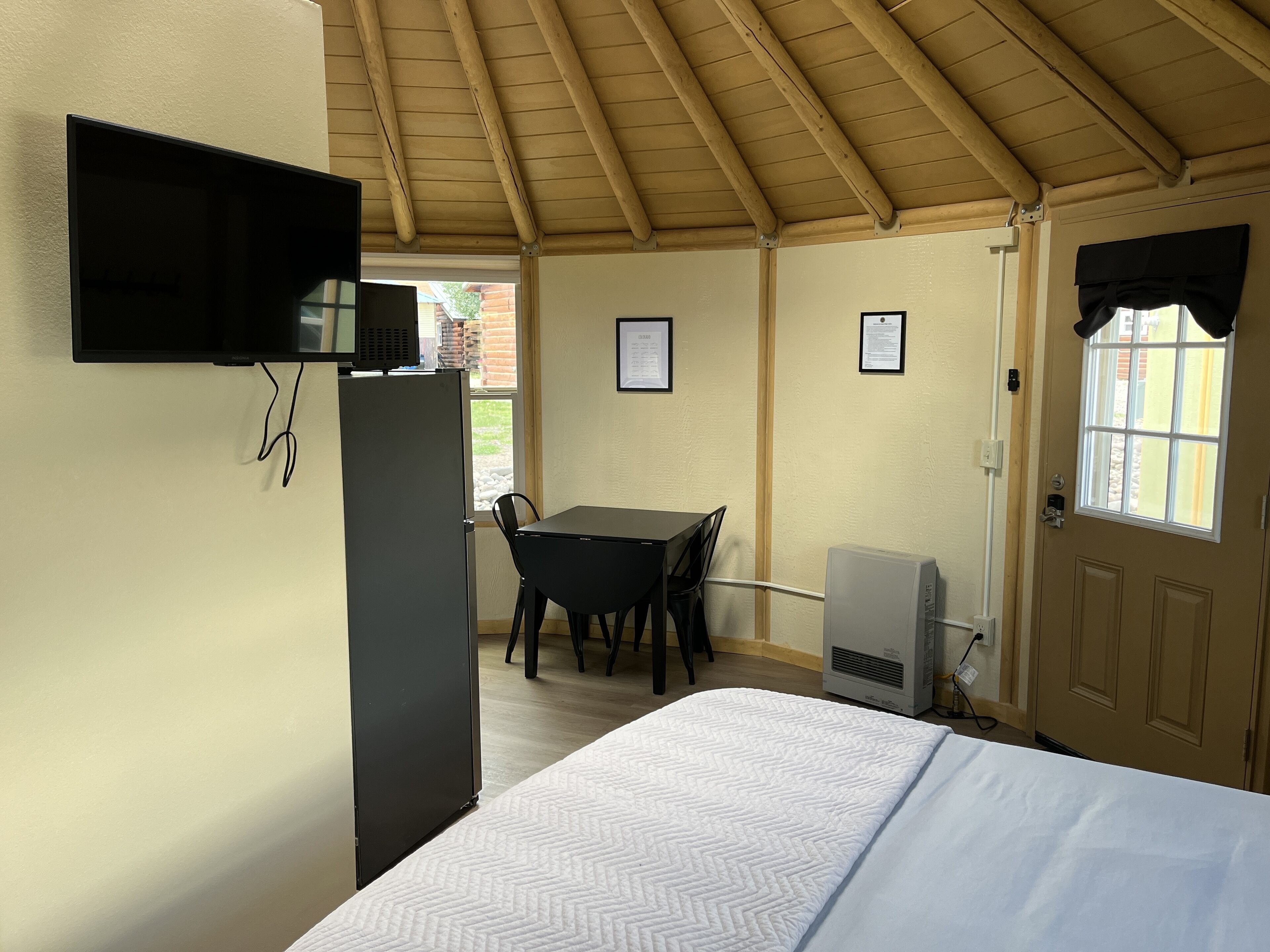 A room with a bed, a desk, a chair, a television, and a door with a window.