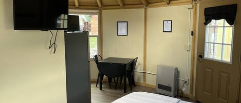 A room with a bed, a desk, a chair, a television, and a door with a window.