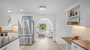 Una cocina moderna con armarios blancos, un refrigerador de acero inoxidable y una encimera de madera.
