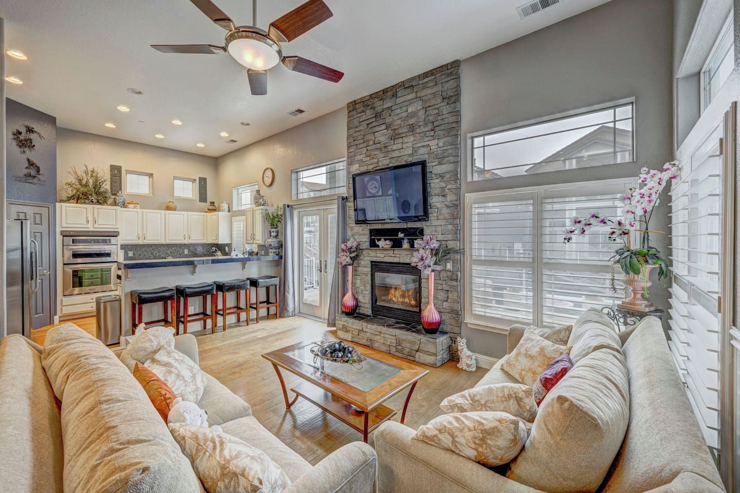 A spacious living area with a fireplace, a sofa set, a coffee table, and a television mounted above the fireplace.