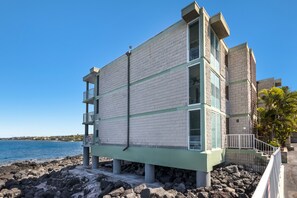 Un edificio de varios pisos con fachada de azulejos, situado cerca de una costa rocosa y vistas al mar.