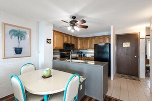A kitchen with wooden cabinets, a black refrigerator, and a ceiling fan.