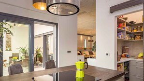 Een moderne keuken met een zwart inductiekookplaatje, een gele koffiepot en een inbouwpantry met diverse etenswaren.