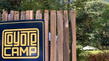 A wooden fence with a sign that reads "Coyote Camp" and another sign indicating "Sites 21-26".