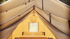 Une tente équipée d’un lit, d’une fenêtre et d’une lanterne.