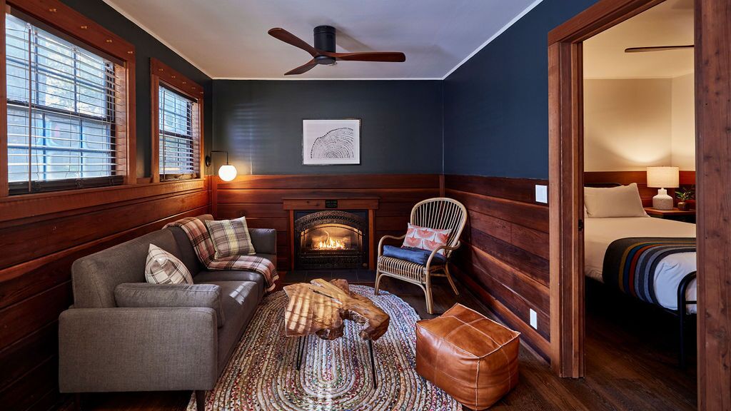 A cozy room with a fireplace, a sofa, a chair, and a bed.