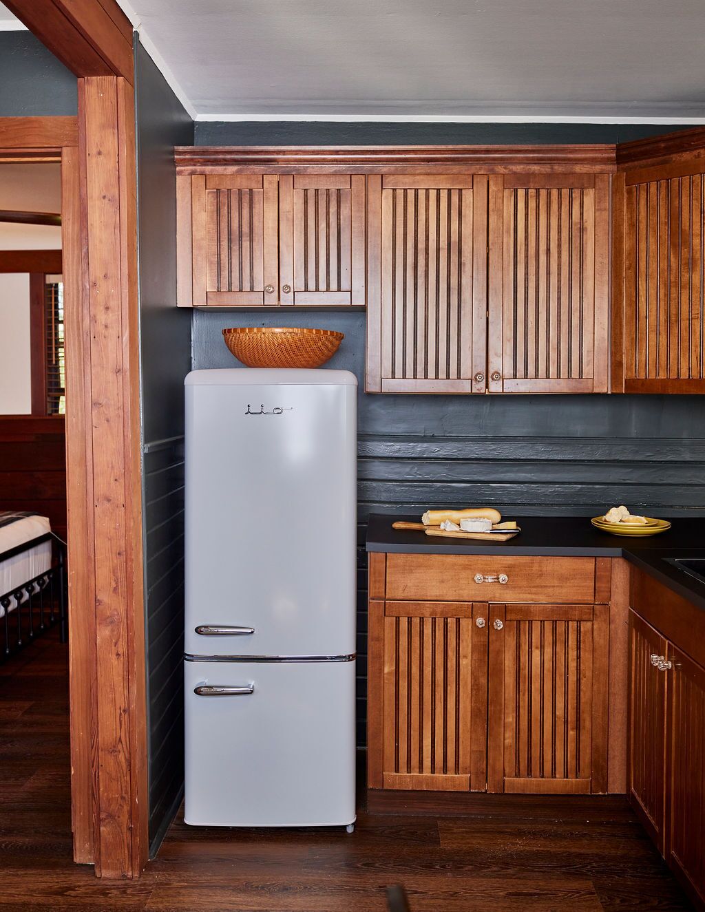 Una cocina funcional con armarios de madera, un refrigerador blanco y una encimera negra.