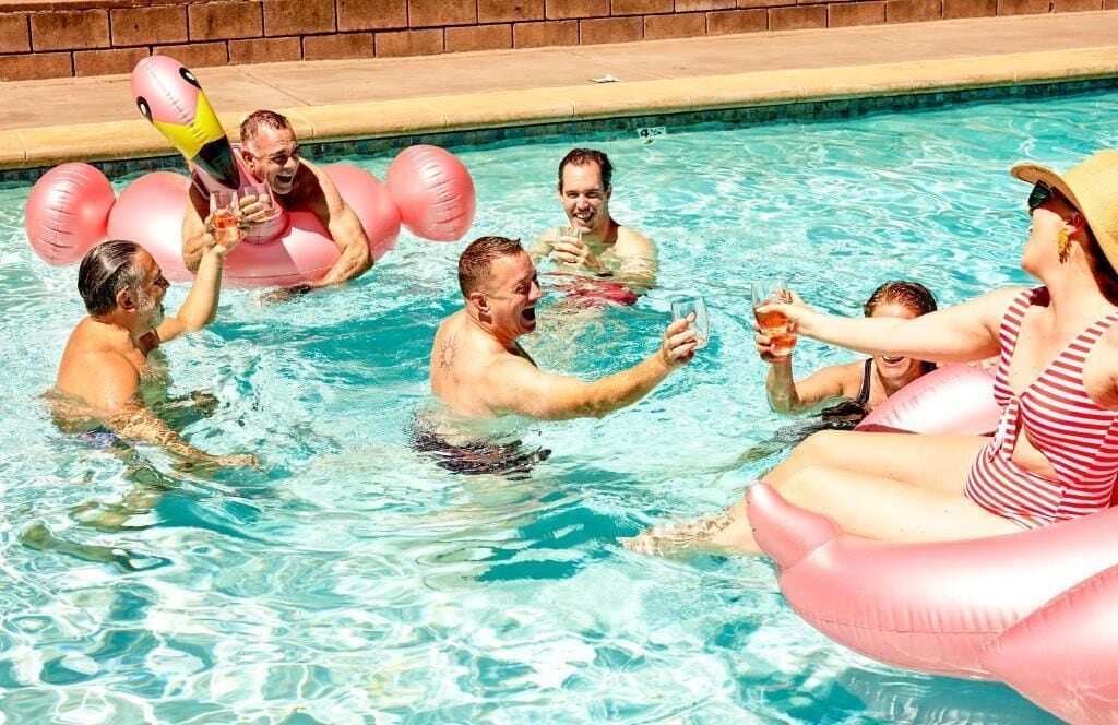 A swimming pool with people enjoying themselves, some on inflatable floats.