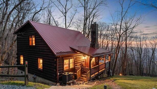 A log cabin with a porch, a chimney, and a view of the surrounding forest. - Jacuzzi / Views of Grandfather Mountain / Secluded (Seven Devils)