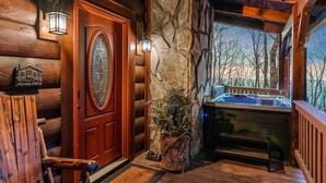 A log cabin with a wooden door, stone wall, and a hot tub. - Jacuzzi / Views of Grandfather Mountain / Secluded (Seven Devils)