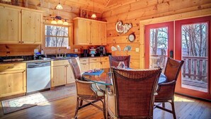 A wooden cabin kitchen with a dining area, wooden cabinets, a dishwasher, and a coffee sign. - Jacuzzi / Views of Grandfather Mountain / Secluded (Seven Devils)