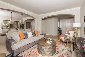 Un salon moderne avec un canapé gris, une table basse ronde et un tapis coloré.