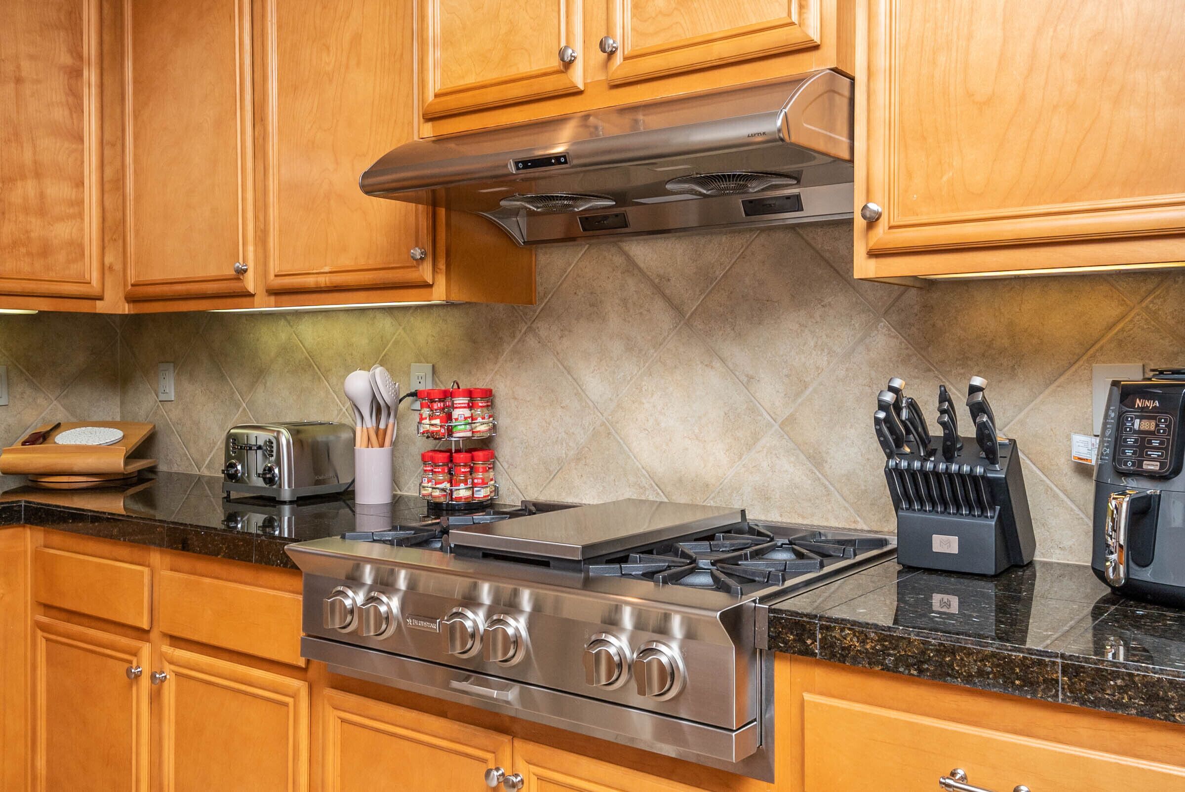 A kitchen with wooden cabinets, a stainless steel stove, a toaster, and a knife block.
