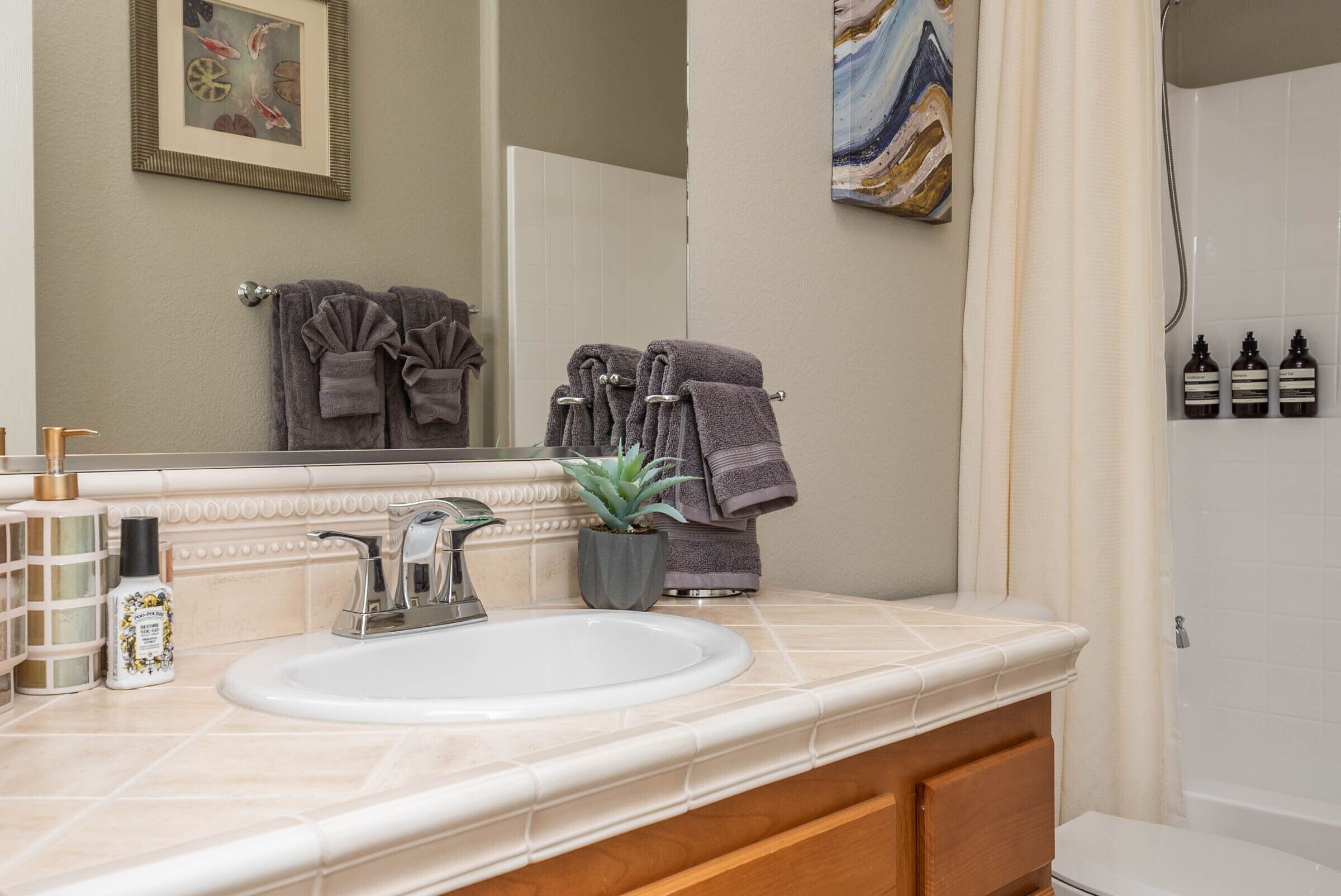 A bathroom with a white sink, a mirror, a potted plant, and a towel rack.