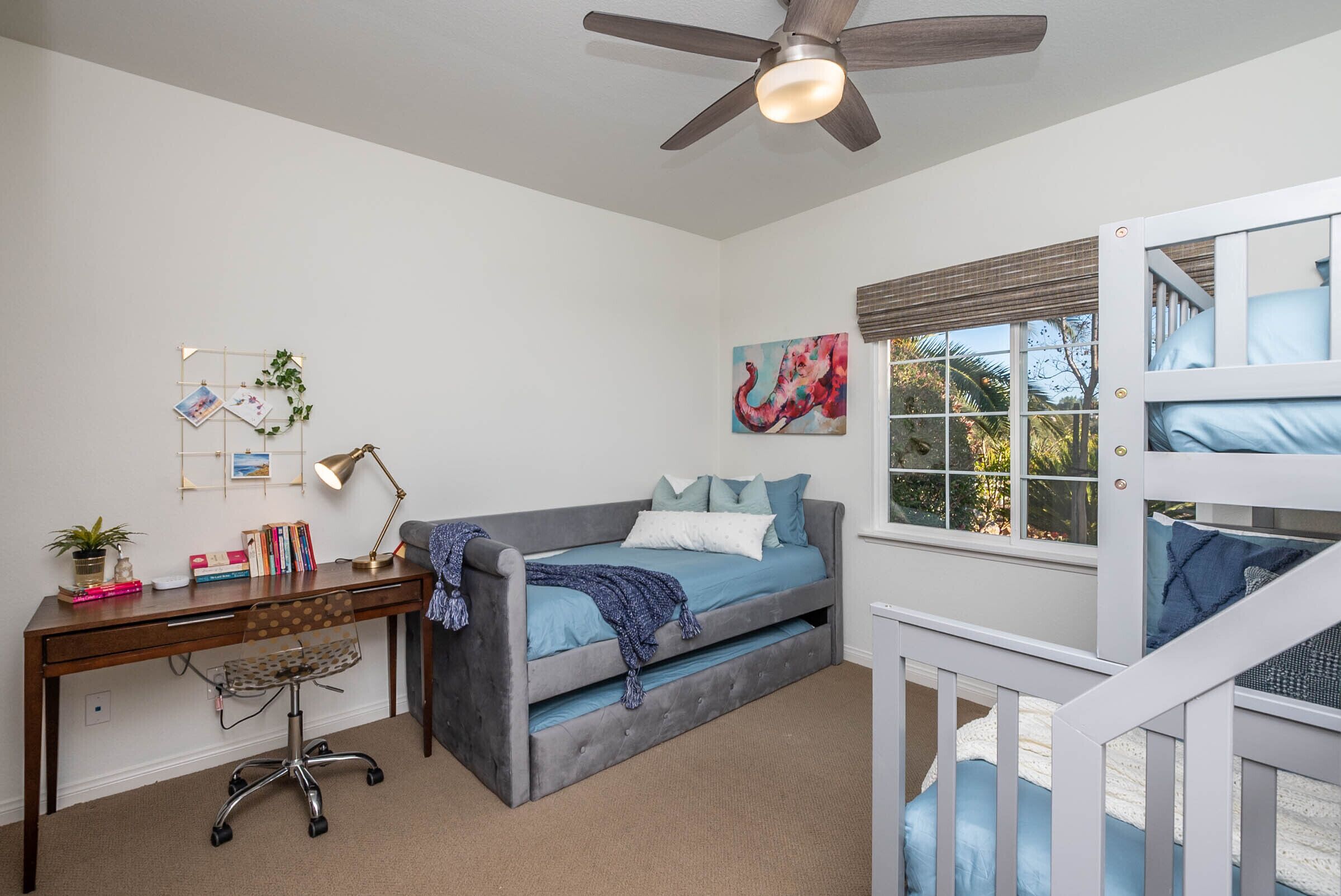 A bedroom with a bed, desk, chair, and a window with blinds.