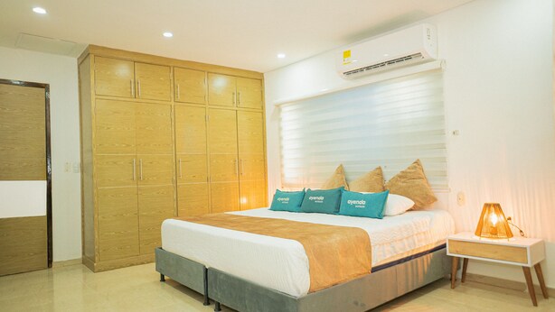 Un dormitorio con cama, armario, aire acondicionado y lámpara de noche.