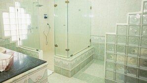 Un baño con ducha envuelta en vidrio, lavabo y azulejos decorativos.