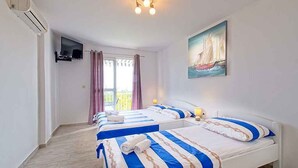 Habitación de hotel con dos camas, televisión, un cuadro y balcón.