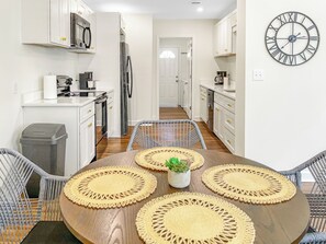 A modern kitchen with white cabinets, a stainless steel refrigerator, and a wall clock.