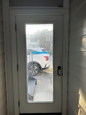 Een witte deur met een ruit, een cijferslot en een blauw bord waarop staat 'ALLEEN VOOR GASTEN'.