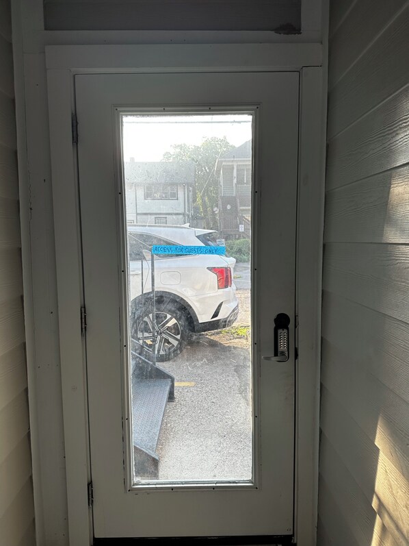 A white door with a glass panel, a keypad lock, and a blue sign stating 'ACCESS FOR GUESTS ONLY.'