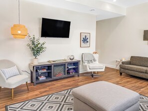 A living room with a flat-screen TV, a sofa, a chair, a side table, and a patterned rug.