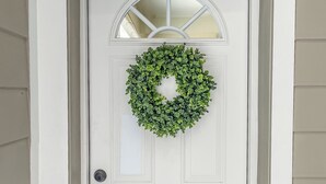 Une porte blanche ornée d’une fenêtre ronde et d’une guirlande verte.