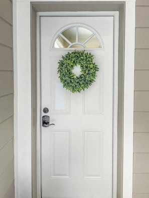 A white door with a circular window and a green wreath.