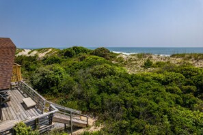 Une terrasse en bois offrant une vue sur l’océan et les dunes.