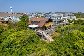 A coastal residential area with multiple houses, a prominent water tower, and lush greenery.
