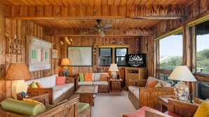 L’intérieur chaleureux d’un chalet avec des murs en bois, un ventilateur de plafond et une enseigne indiquant « Coastal Carolina Cottages ».