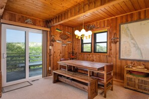 A wooden interior with a table, benches, a map, and a window overlooking greenery.