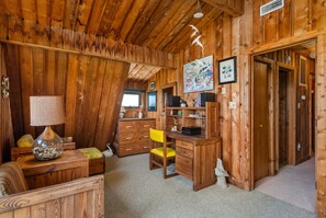 A cozy wooden room with a desk, chair, lamp, and decorative items. - Dunesbury:Oceanfront, dog-friendly, four bedrooms, mini-vacation anytime! (Corolla)