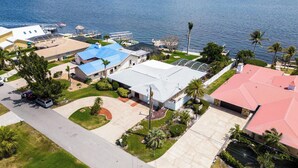 A residential area with houses, a boat dock, and a view of the water. - Picturesque Watefront, Heated Pool, Ping Pong Table - Villa Sunset Riverhouse - Roelens Vacations (Cape Coral)