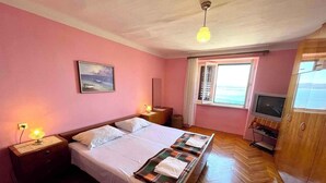 Een slaapkamer met een bed, nachtkastjes, een televisie en een raam met uitzicht.