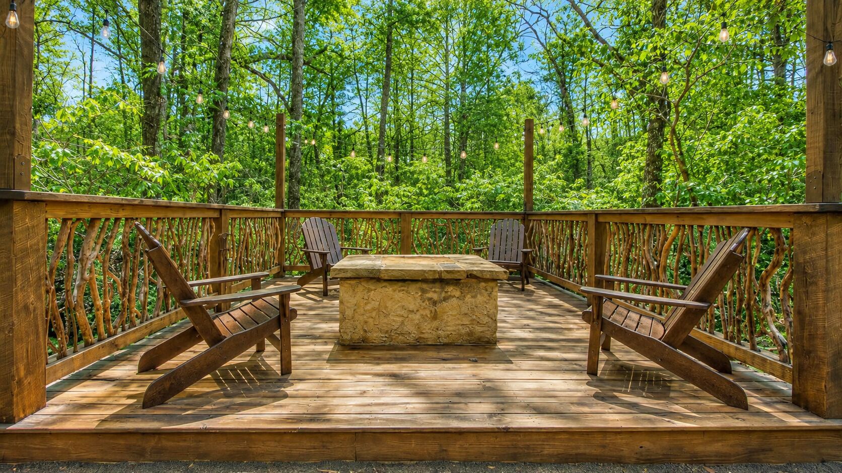 An outdoor deck with wooden railings, benches, and a stone table.