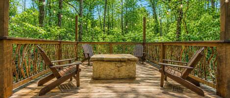 An outdoor deck with wooden railings, benches, and a stone table.