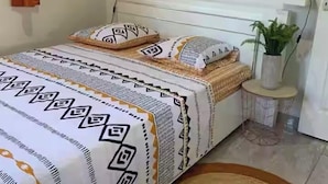 Een verzorgde slaapkamer met een bed, een nachtkastje met een lamp, een wanddecoratie en een potplant.
